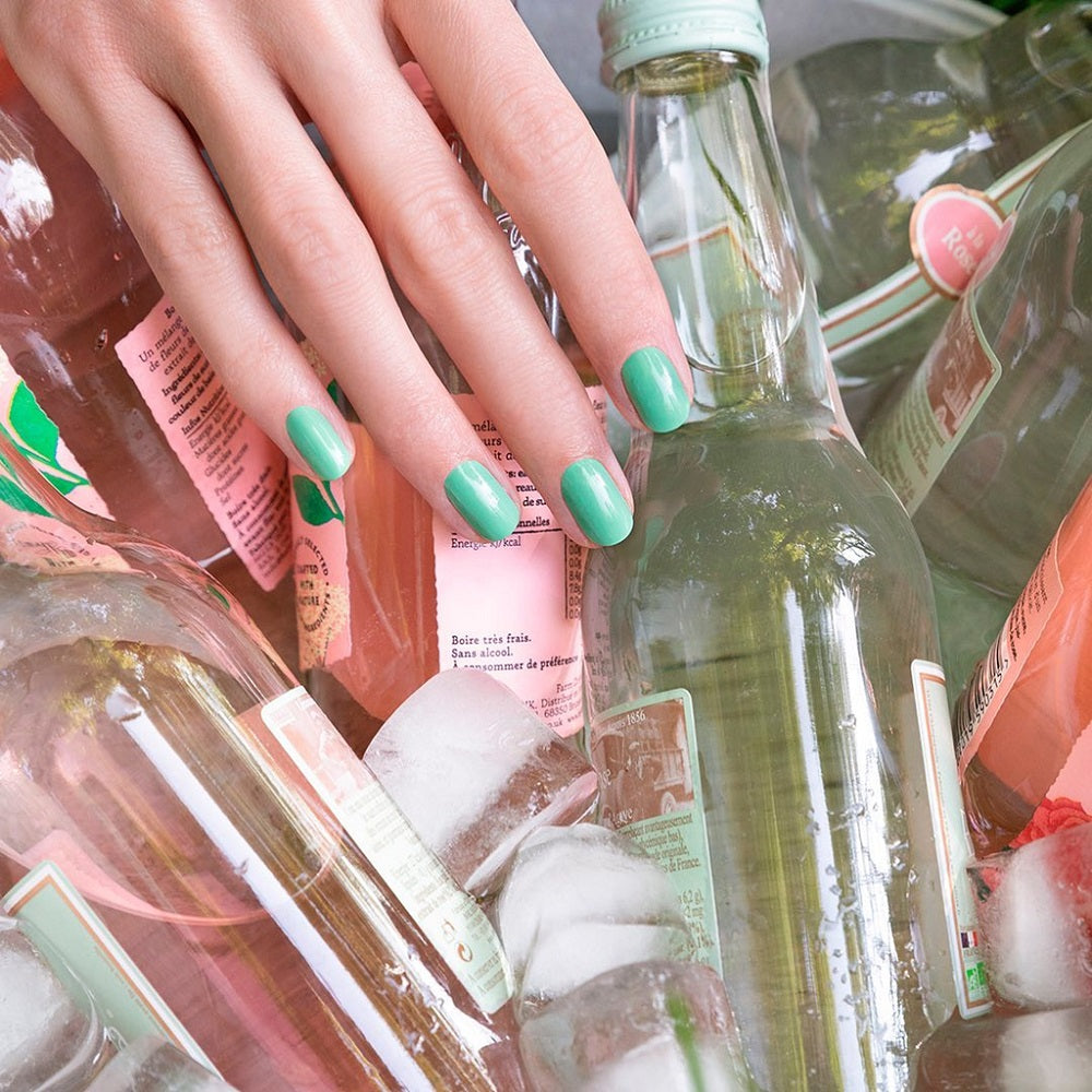 amande manucurist pose sur les ongles avec bouteilles en verre