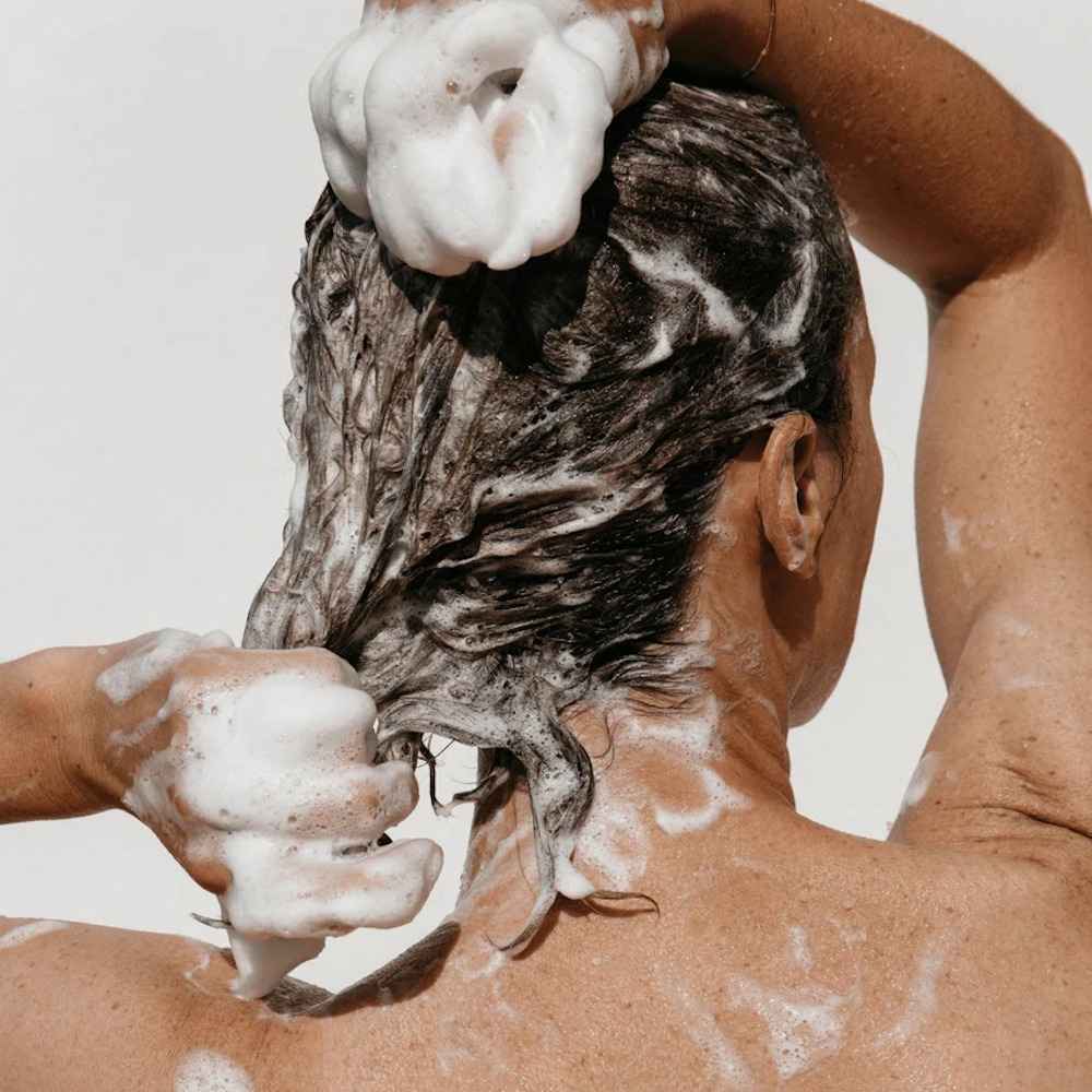 Femme qui utilise le shampoing exfoliant