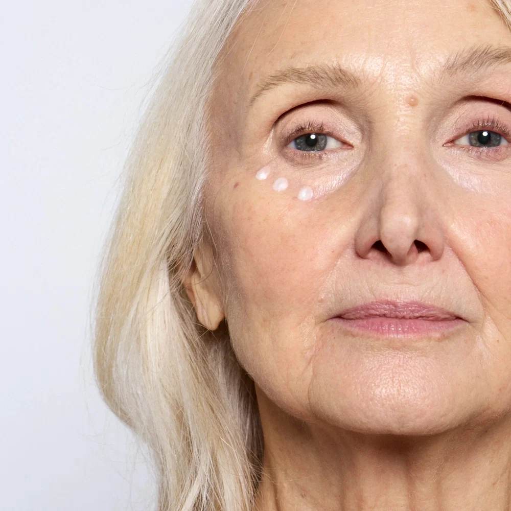Application du soin contour des yeux Endro en points sous l'œil sur une peau mature