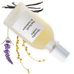 Flacon rechargeable Patchouli & Cachemire Veronika Loubry posé sur des brins de Lavande, de Mimosa et de Vanille