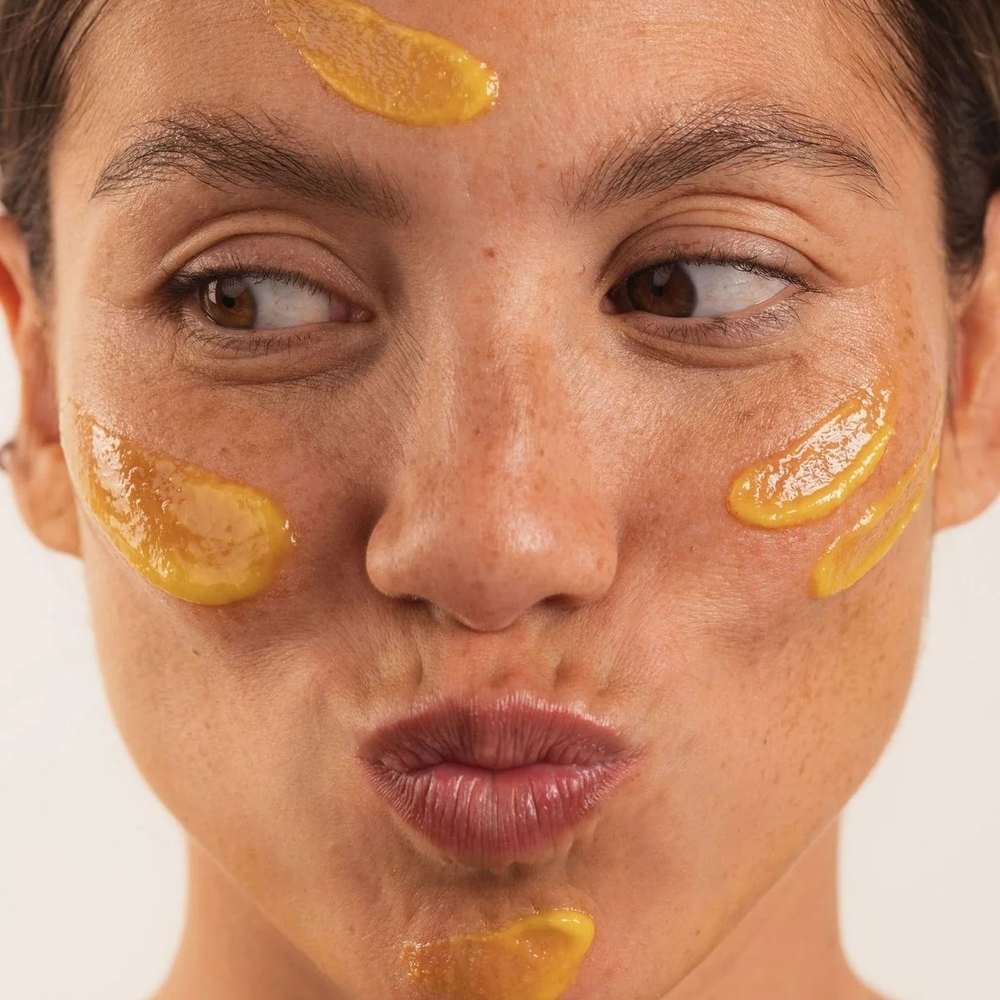 Femme portant des touches de masque exfoliant ambré sur le front, les joues et le menton