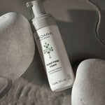 Flacon de la Mousse Purifiante Mádara posé sur des galets