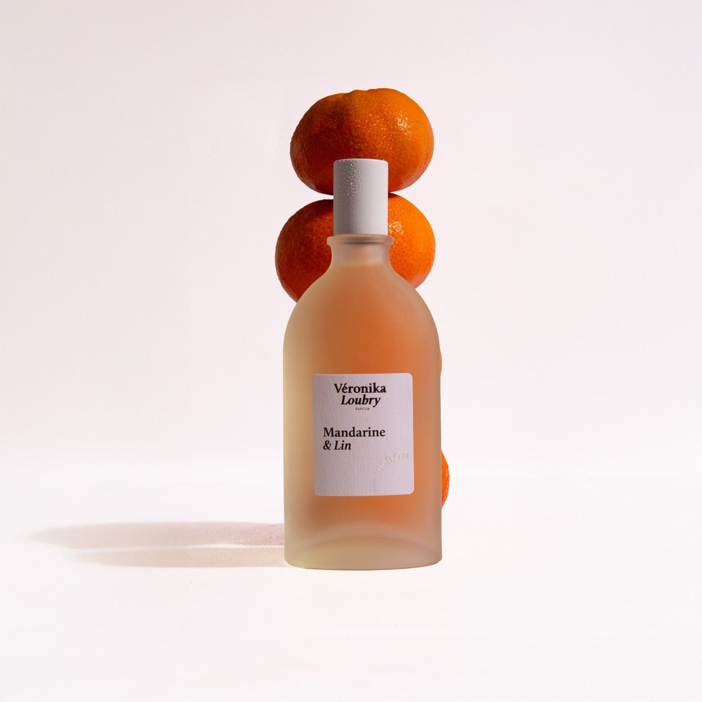 Flacon de parfum naturel Mandarine & Lin Veronika Loubry devant des Mandarines empilées