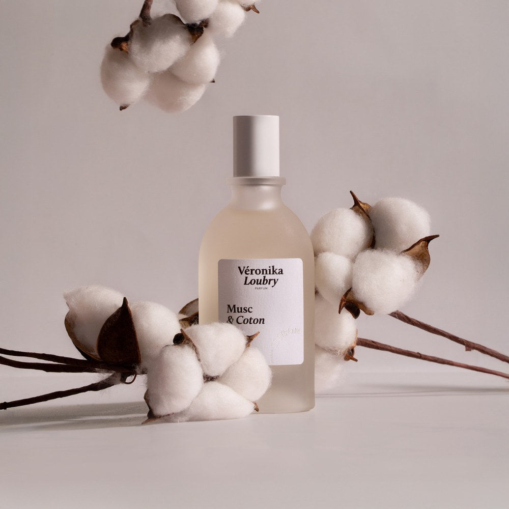Flacon de parfum naturel Musc & Coton Veronika Loubry entouré de branches de fleurs de Coton