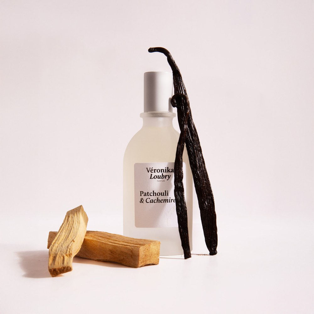 Flacon de parfum naturel Patchouli & Cachemire Veronika Loubry entouré de gousses de Vanille et de bois de Santal