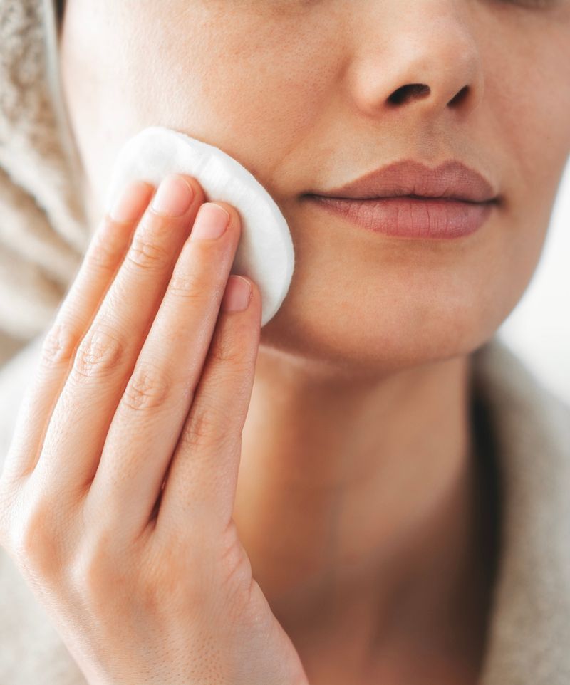 Femme rinçant son visage avec un coton d'eau florale