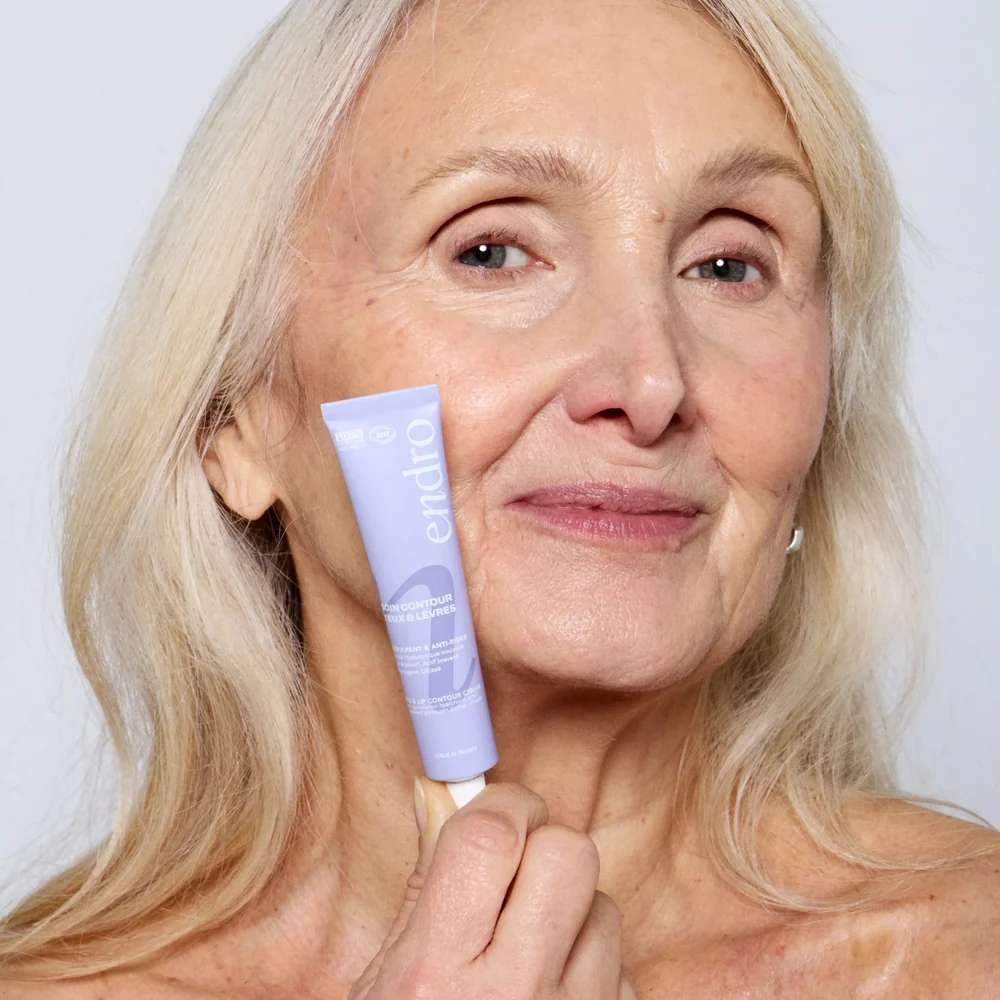 Femme aux cheveux blancs tenant le soin anti-âge contour yeux et lèvres Endro
