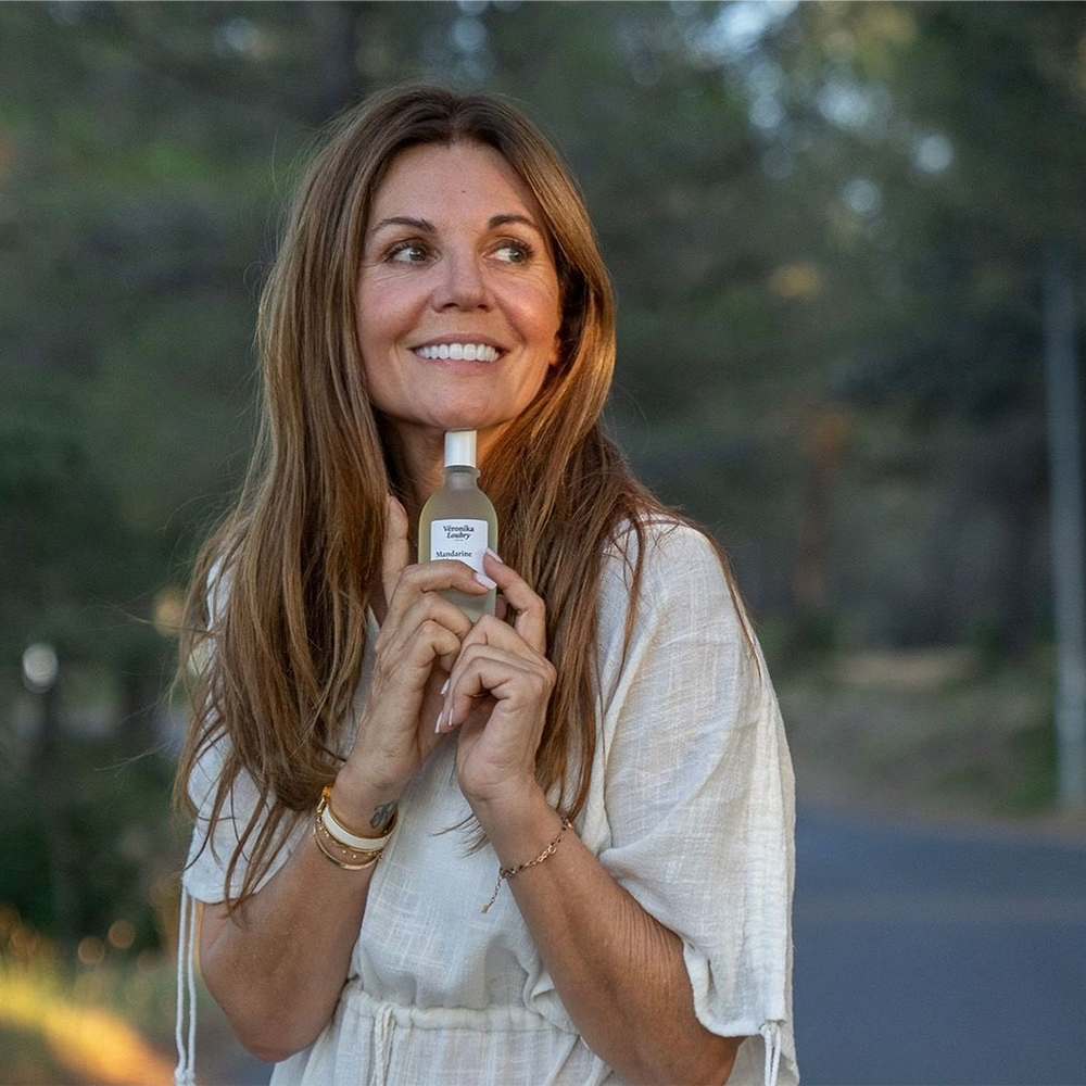 Véronika Loubry tenant un flacon de sa collection de parfums naturels fabriqués à Grasse